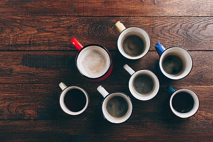 mehrere gefüllte Kaffeebecher von oben, die auf einem Holztisch platziert sind